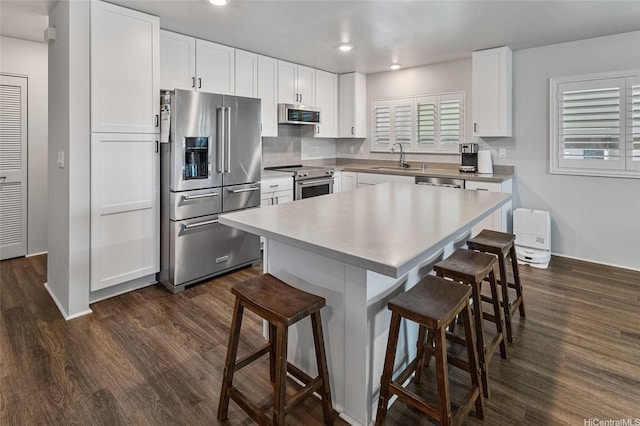 kitchen featuring white cabinets, stainless steel appliances, a kitchen breakfast bar, and a sink