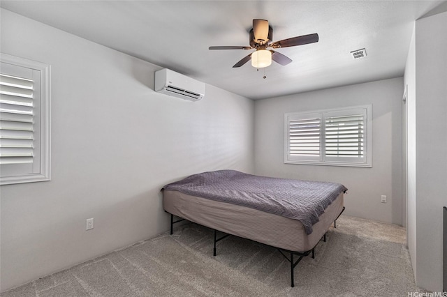 carpeted bedroom with visible vents, a ceiling fan, and a wall unit AC
