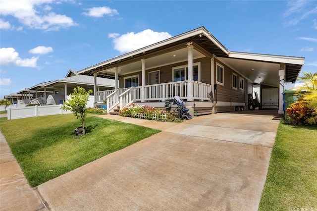 farmhouse featuring an attached carport, fence, concrete driveway, a front lawn, and a porch