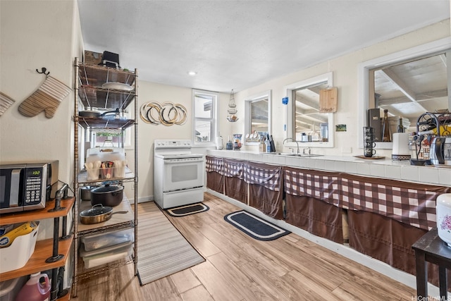 54-266 Kawaihemo Pl, Hauula, HI 96717 - kitchen featuring stainless steel microwave, light wood-style flooring, a sink, white electric range, and tile countertops
