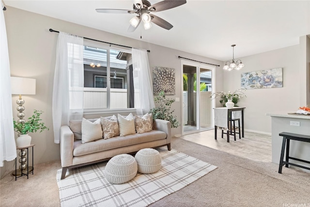 carpeted living room featuring ceiling fan with notable chandelier