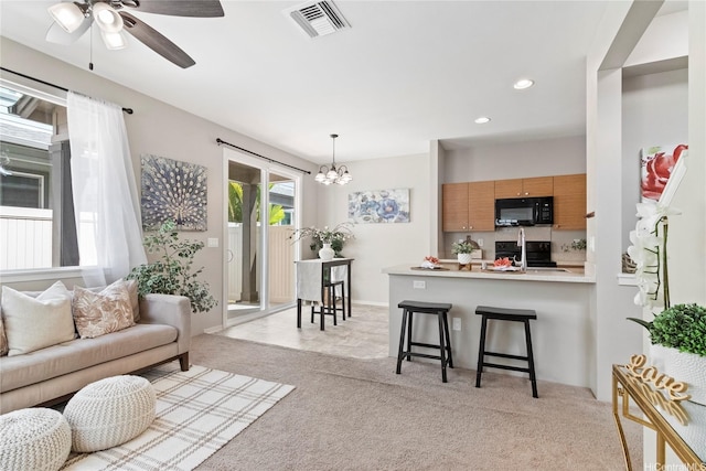 living room featuring visible vents, recessed lighting, ceiling fan with notable chandelier, and light carpet