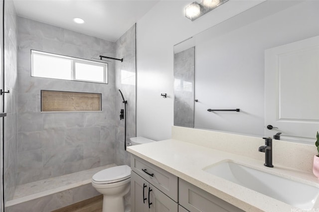full bath featuring toilet, vanity, and tiled shower