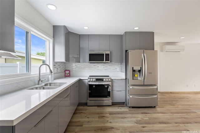 kitchen with stainless steel appliances, light wood-style flooring, a sink, modern cabinets, and gray cabinets
