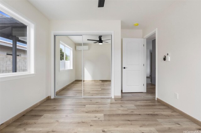 interior space featuring an AC wall unit, baseboards, wood finished floors, and a closet
