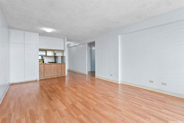 1031 Ala Napunani St Unit 401, Honolulu, HI 96818 - unfurnished living room with baseboards, light wood-type flooring, and a textured ceiling
