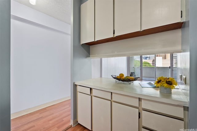 1031 Ala Napunani St Unit 401, Honolulu, HI 96818 - kitchen featuring light wood-type flooring, light countertops, and white cabinets