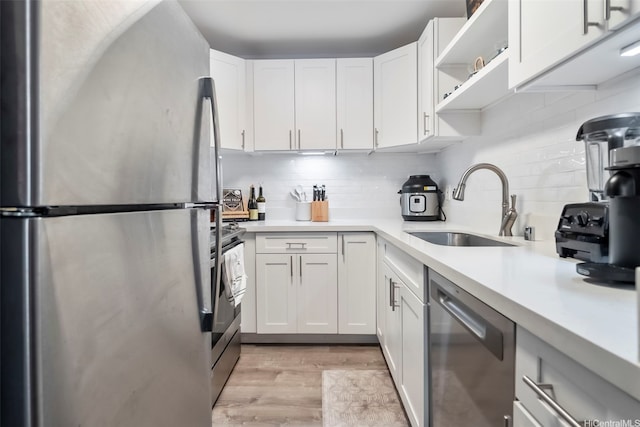 kitchen with decorative backsplash, appliances with stainless steel finishes, light wood-type flooring, a sink, and light countertops