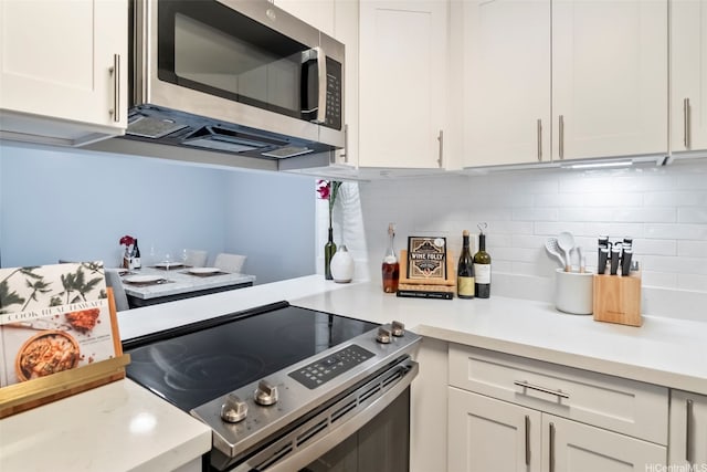 kitchen with light countertops, appliances with stainless steel finishes, tasteful backsplash, and white cabinetry