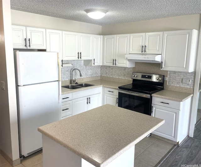 kitchen featuring electric stove, a sink, white cabinetry, under cabinet range hood, and freestanding refrigerator