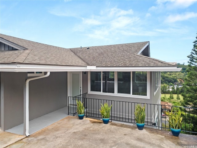 exterior space featuring roof with shingles, stucco siding, and fence