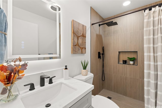 bathroom with recessed lighting, tiled shower, vanity, and toilet