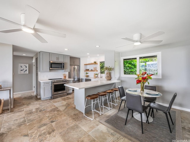 kitchen with light countertops, a ceiling fan, gray cabinetry, and stainless steel appliances