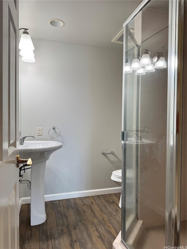 bathroom featuring a sink, toilet, baseboards, wood finished floors, and a shower stall