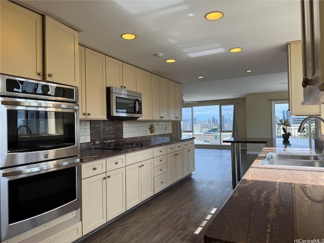 kitchen featuring recessed lighting, backsplash, a sink, appliances with stainless steel finishes, and dark wood-style flooring