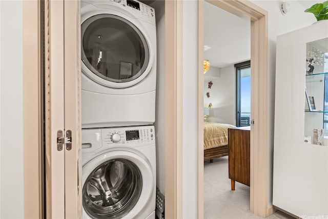 laundry room with stacked washer and clothes dryer and carpet