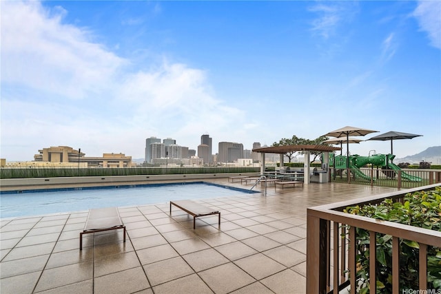 community pool featuring a patio, a city view, and playground community