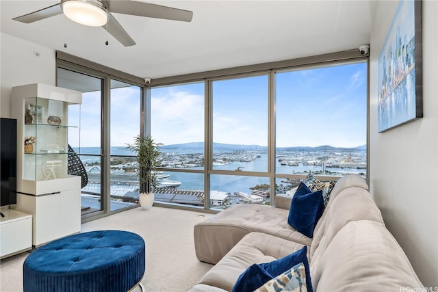 carpeted living room with a water view, floor to ceiling windows, and a ceiling fan