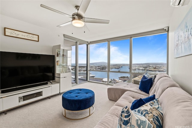 carpeted living area featuring a ceiling fan, a wall of windows, and a water view