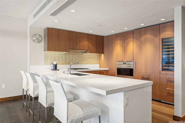 1555 Kapiolani Blvd Unit 1800, Honolulu, HI 96814 - kitchen with stainless steel oven, brown cabinets, dark wood finished floors, modern cabinets, and recessed lighting