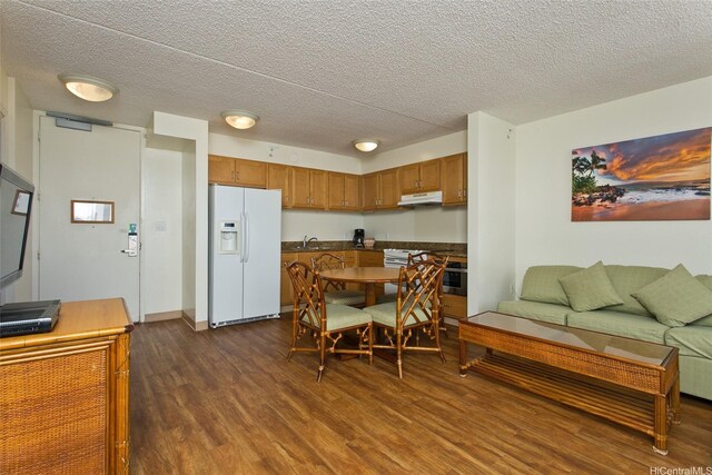 201 Ohua Ave Unit 3006, Honolulu, HI 96815 - kitchen featuring dark wood-style flooring, under cabinet range hood, brown cabinets, a sink, and white fridge with ice dispenser