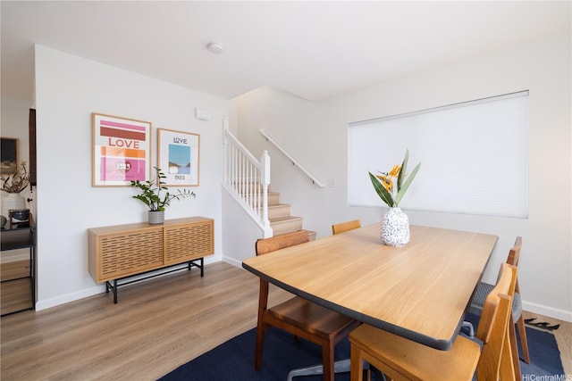 dining room with baseboards, wood finished floors, and stairs