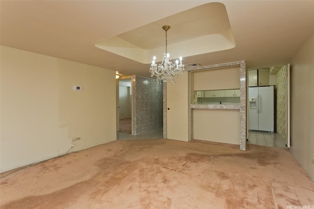 unfurnished dining area featuring a tray ceiling, light carpet, an inviting chandelier, and visible vents