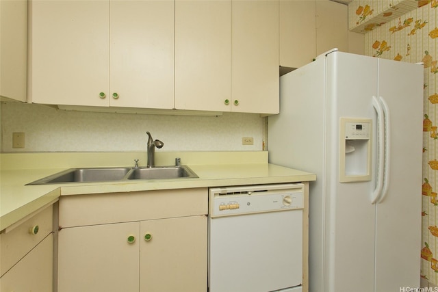 kitchen with light countertops, wallpapered walls, a sink, and white appliances