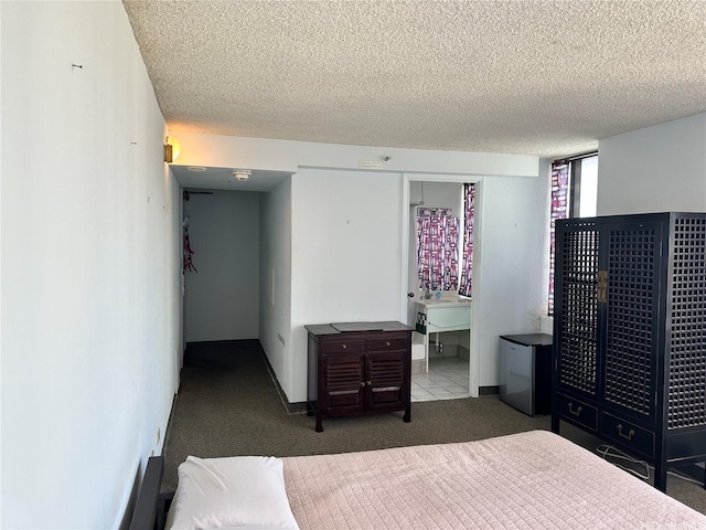 carpeted bedroom with baseboards, freestanding refrigerator, and a textured ceiling
