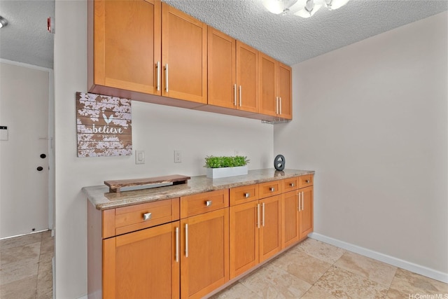 2920 Ala Ilima St Unit 1003, Honolulu, HI 96818 - kitchen with a textured ceiling, baseboards, and light stone counters