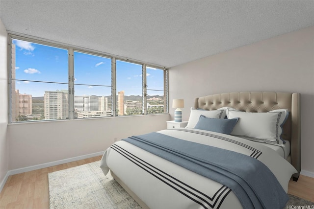 2920 Ala Ilima St Unit 1003, Honolulu, HI 96818 - bedroom featuring wood finished floors, multiple windows, baseboards, and a textured ceiling