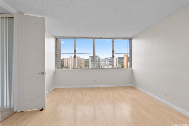 2920 Ala Ilima St Unit 1003, Honolulu, HI 96818 - empty room with wood finished floors, baseboards, a textured ceiling, and a city view