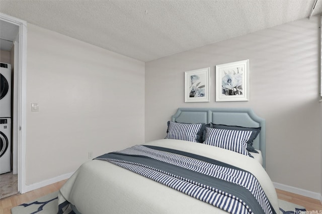 2920 Ala Ilima St Unit 1003, Honolulu, HI 96818 - bedroom with stacked washer / drying machine, light wood-style floors, a textured ceiling, and baseboards