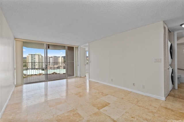 2920 Ala Ilima St Unit 1003, Honolulu, HI 96818 - spare room with estacked washer and dryer, floor to ceiling windows, baseboards, a textured ceiling, and tile patterned flooring