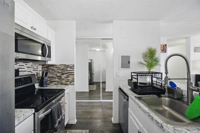 kitchen featuring white cabinetry, tasteful backsplash, a sink, appliances with stainless steel finishes, and dark wood-type flooring