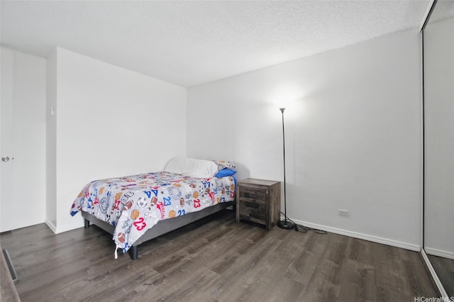 bedroom with a textured ceiling, wood finished floors, and baseboards