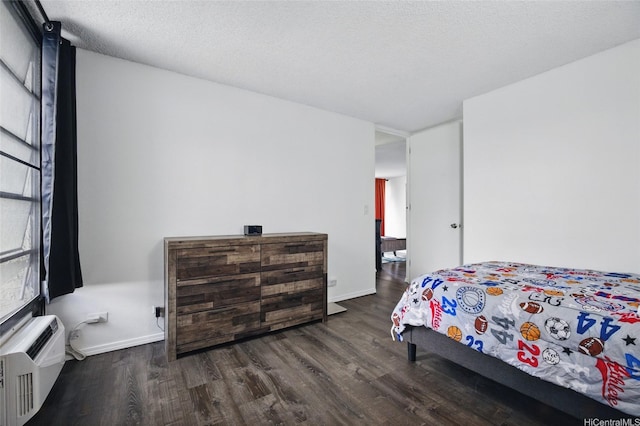 bedroom featuring an AC wall unit, wood finished floors, and baseboards
