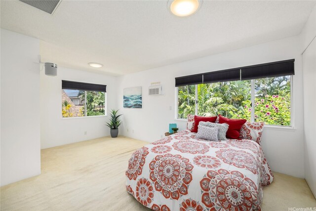 carpeted bedroom featuring visible vents, multiple windows, and a wall mounted AC