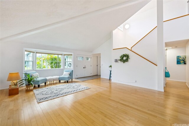 foyer with high vaulted ceiling, baseboards, light wood finished floors, and beam ceiling