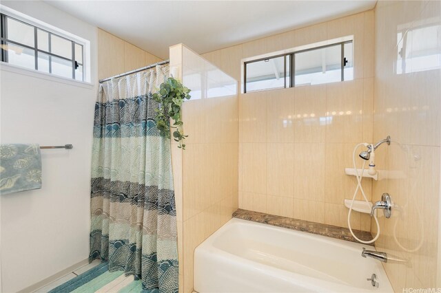 bathroom with a healthy amount of sunlight and shower / bathtub combination with curtain