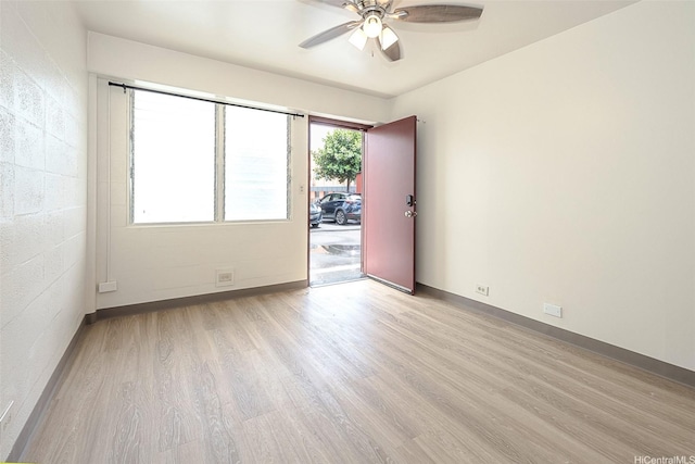 empty room featuring baseboards, light wood-type flooring, and a ceiling fan