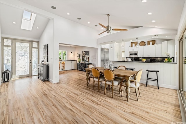 dining room with recessed lighting, a skylight, light wood-style flooring, high vaulted ceiling, and ceiling fan