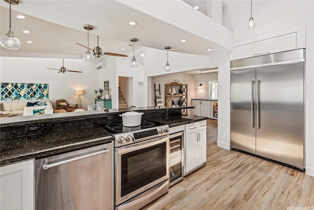 kitchen with a ceiling fan, open floor plan, appliances with stainless steel finishes, white cabinetry, and wine cooler