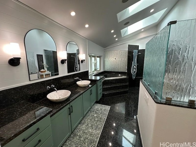 bathroom featuring a bath, a sink, double vanity, granite finish floor, and vaulted ceiling with skylight