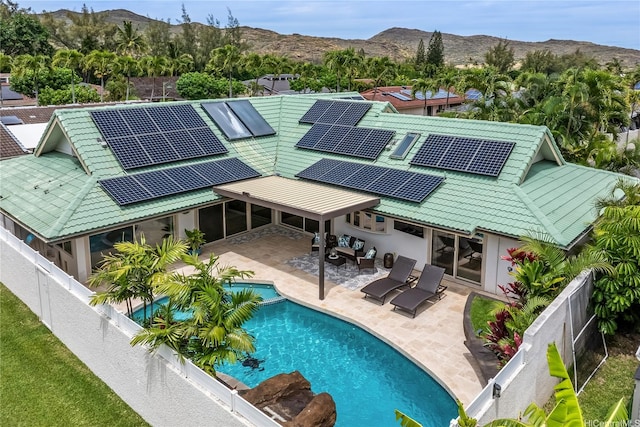 back of property featuring a fenced backyard, roof mounted solar panels, a mountain view, and a patio