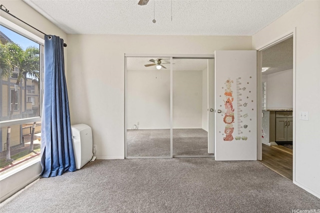 unfurnished bedroom featuring a closet, ceiling fan, a textured ceiling, and carpet floors