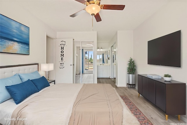 bedroom featuring light wood-style floors, ensuite bath, and a ceiling fan