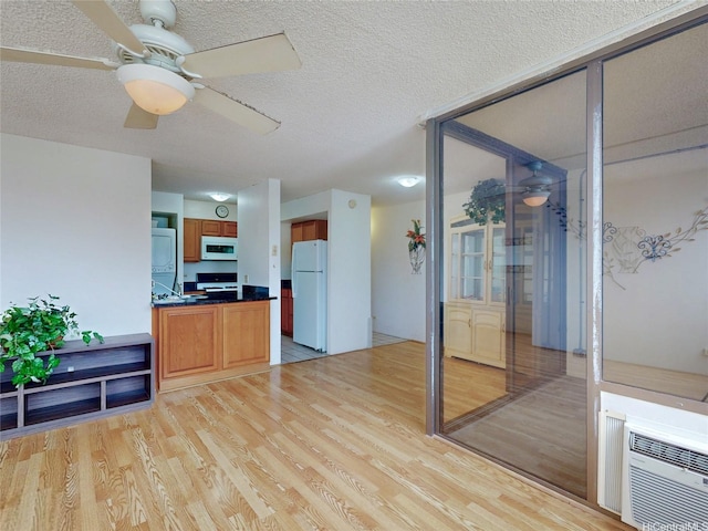 1571 Piikoi St Unit 1601, Honolulu, HI 96822 - interior space with light wood finished floors, a textured ceiling, a wall unit AC, dark countertops, and white appliances