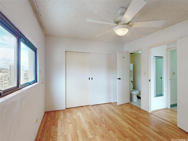 1571 Piikoi St Unit 1601, Honolulu, HI 96822 - unfurnished bedroom with a textured ceiling, wood finished floors, a closet, and ceiling fan