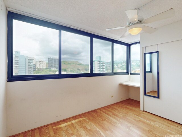 1571 Piikoi St Unit 1601, Honolulu, HI 96822 - empty room with a view of city, a ceiling fan, a textured ceiling, and light wood-style flooring
